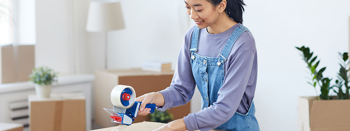 end of tenancy moving out, asian woman packing boxes and sealing them with tape