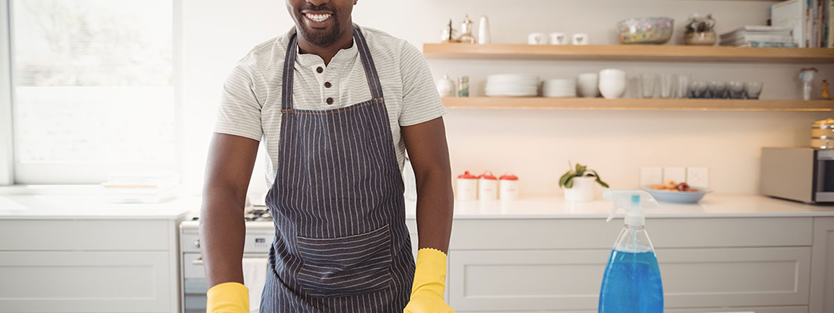 man cleaning the kitchen worktop with yellow rubber gloves and cloth