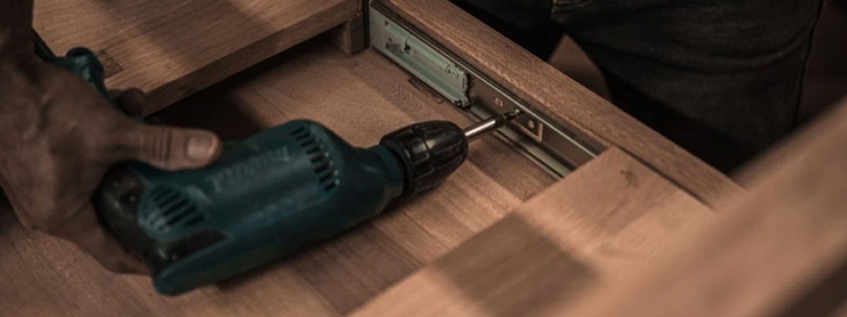A property manager is using a drill to fix flooring