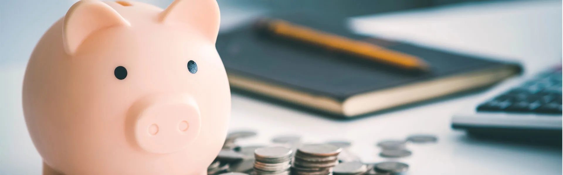 A pink piggy bank sits on top of a neat and clean desk