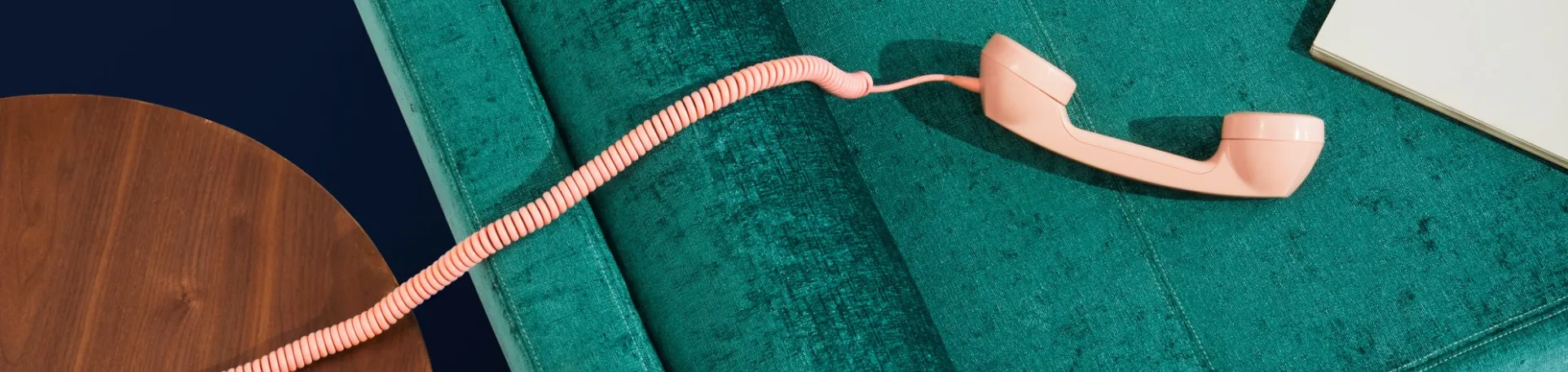 A shell pink phone is laying out on a crushed velvet sofa