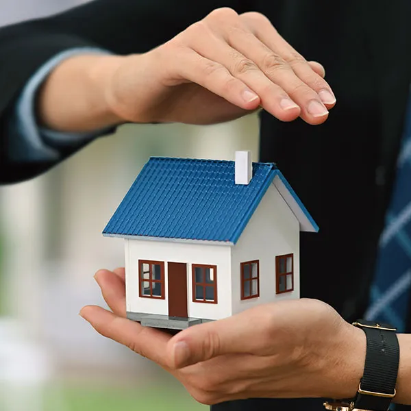 a man shielding a model house with his hands to signify property management 